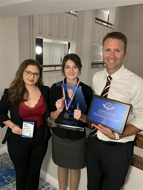Gabrielle Redinger, Braelyn Fletcher with her first place trophy, and DECA Advisor Brandon Mefford